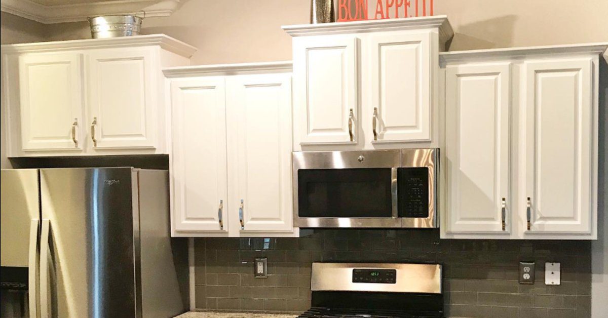 Kitchen with freshly painted white cabinets, stainless steel appliances, gray tile backsplash, and modern brushed nickel hardware.