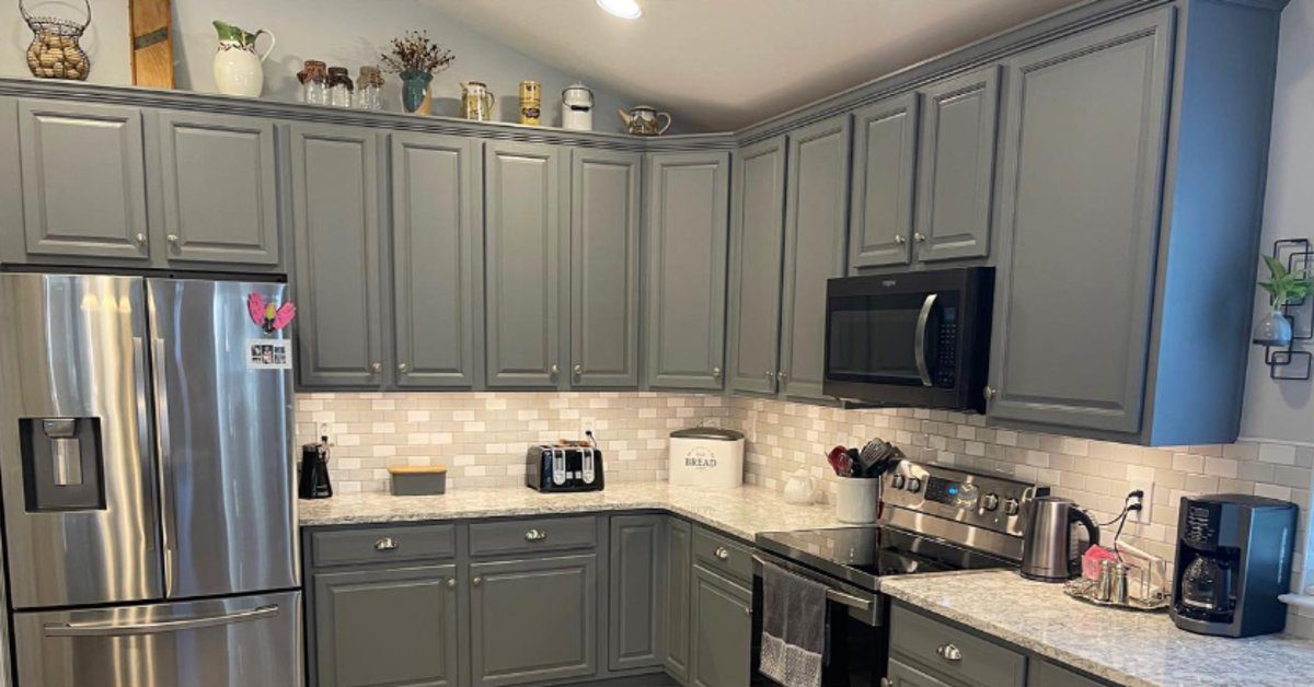Updated kitchen with gray painted cabinets, white subway tile backsplash, granite countertops, and stainless steel appliances.