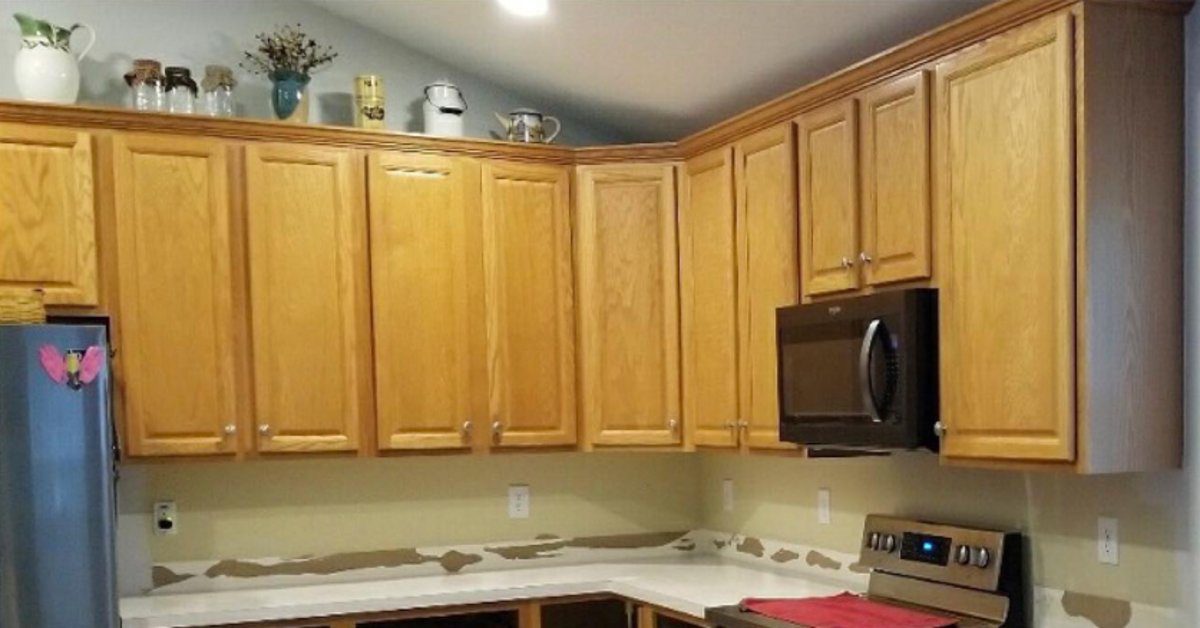 Kitchen featuring natural wood cabinets, laminate countertops, and black appliances prior to cabinet painting and updates.